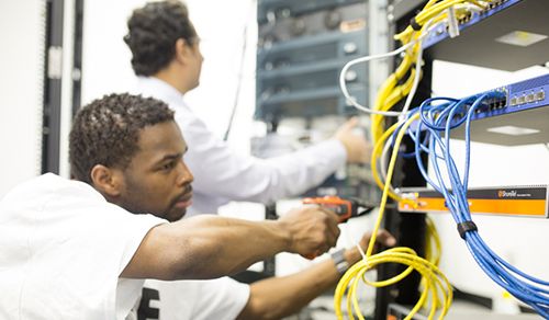 two technicians pinning down cables on a server.